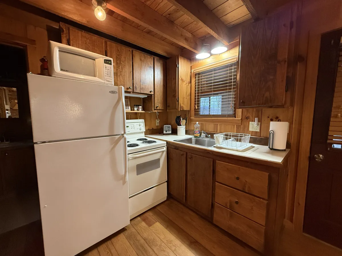 A well-equipped kitchen with wood cabinetry, a white refrigerator, stove, and sink—all the essentials for preparing hearty meals. The space is functional yet warm, making it inviting for family meals, baking, or gathering for a snack.