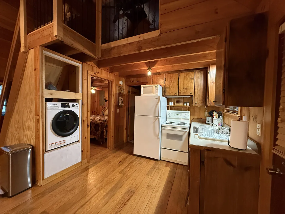 A rustic kitchen scene with wooden cabinetry, modern appliances, and a staircase leading to the upper level. The space is practical for preparing hearty breakfasts before heading out for the day’s adventures and for coming together at mealtime.